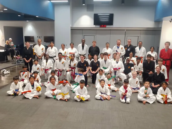 Fulshear Family Karate students of all ages holding up their new colored belts with their instructors