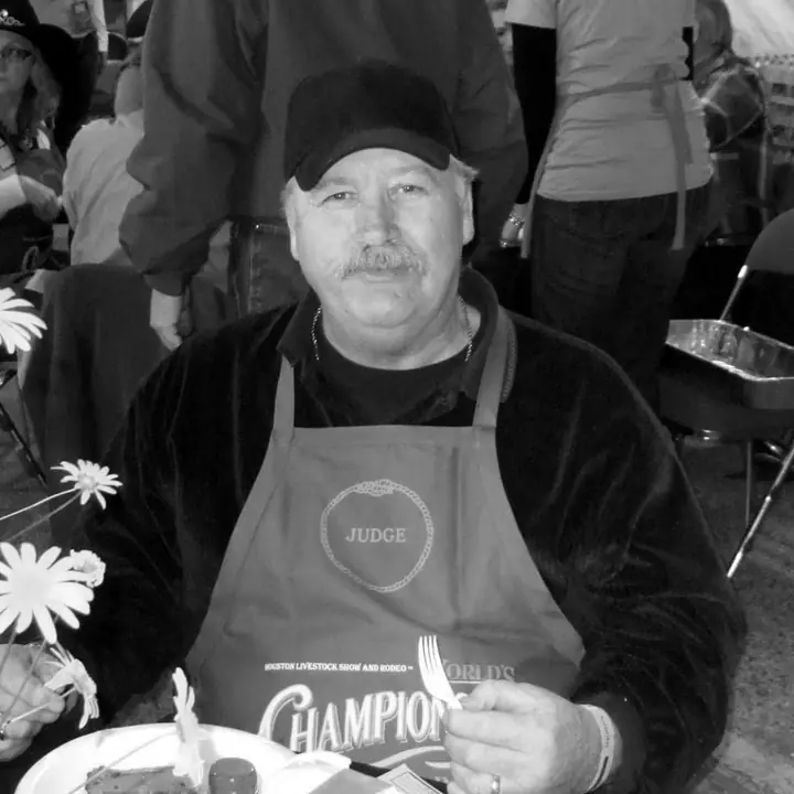 Bill Ramsey smiling, wearing a judge's apron at the Houston Livestock Show and Rodeo Bar-B-Que contest